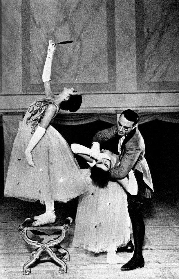 George Balanchine holding Tamara Toumanova in a backbend and Natalie Strakhova standing on a stool looking up into a handheld mirror in “Cotillon”